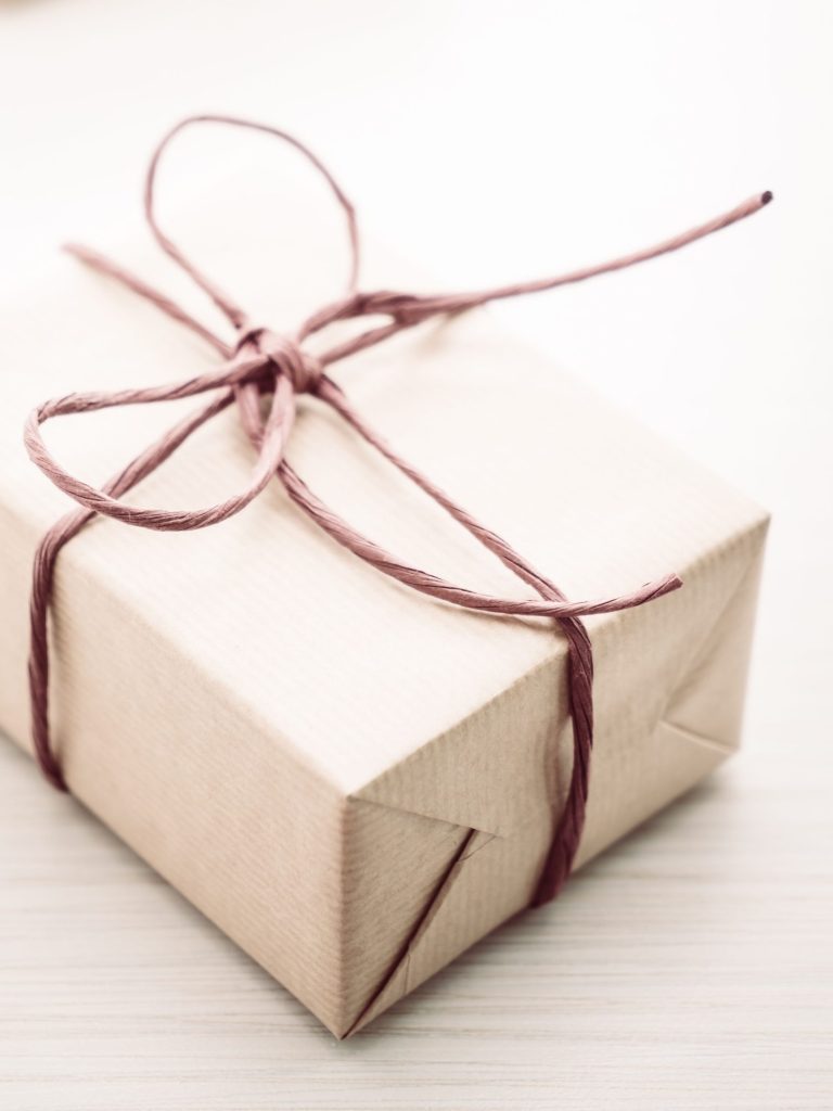 Geschenkideen. Geschenkverpackungen in braunem Papier mit rotem Band, auf hellem Hintergrund.